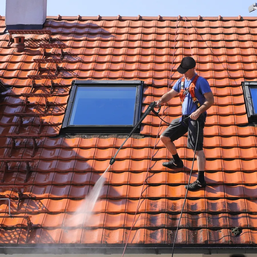 Nettoyage de toit en tuiles | Les Toitures De Louis Homme nettoyant un toit en tuiles avec un jet d'eau
